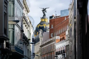 The ornate Beaux-Arts facade and golden dome of the Metropolis Building in Madrid at the intersection of Calle de Alcalá and Gran Vía.