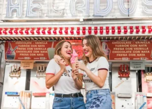 Two friends enjoying the teaching English in Madrid lifestyle by sharing ice cream at a local feria.