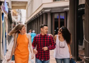 Three friends walking together through a classic Madrid street with columns, laughing and talking in a relaxed social setting.